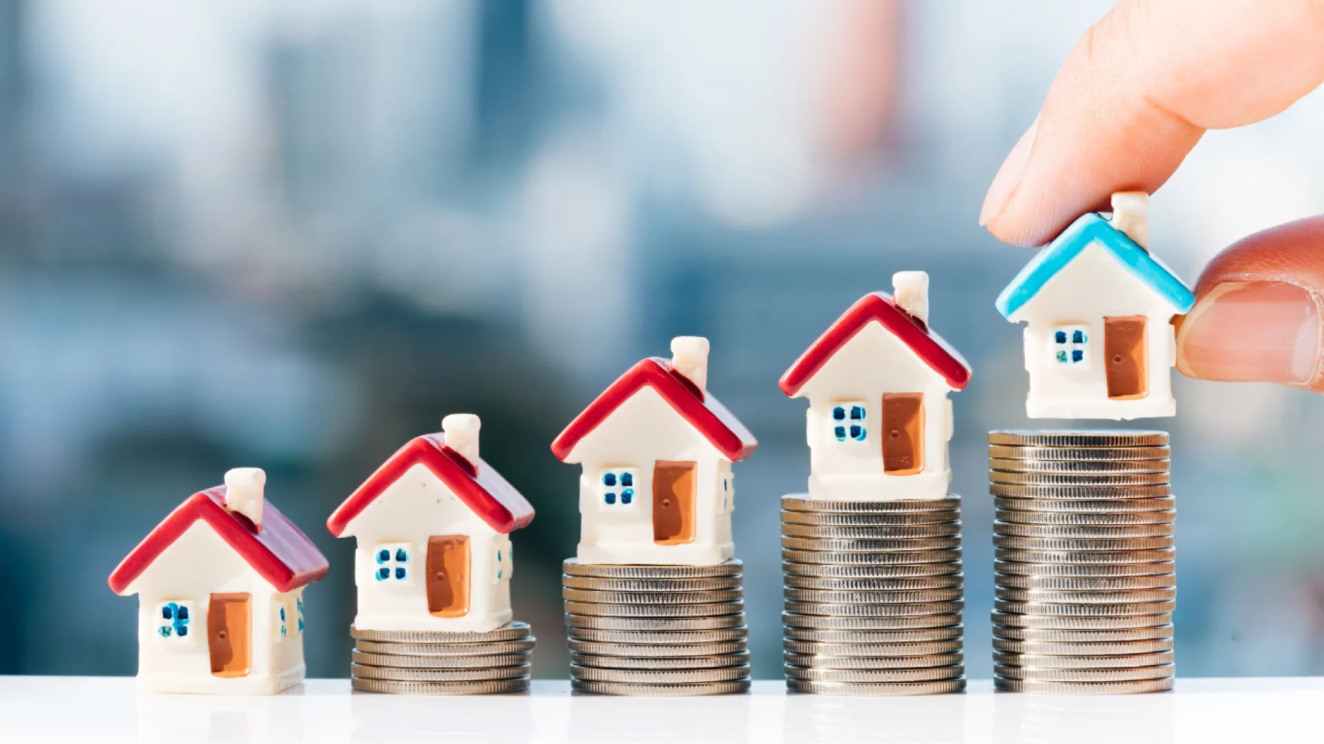 Miniaturhäuser auf Münzstapeln als Symbol für Immobilienfinanzierung